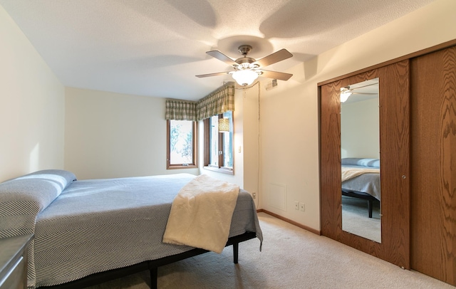 bedroom featuring ceiling fan, light carpet, and a textured ceiling