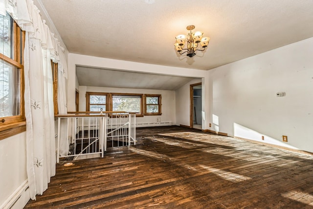 unfurnished room with dark wood-type flooring, a baseboard heating unit, a chandelier, vaulted ceiling, and a textured ceiling