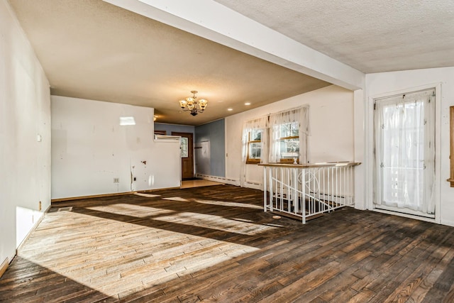 spare room featuring a notable chandelier, dark hardwood / wood-style floors, a healthy amount of sunlight, and a textured ceiling