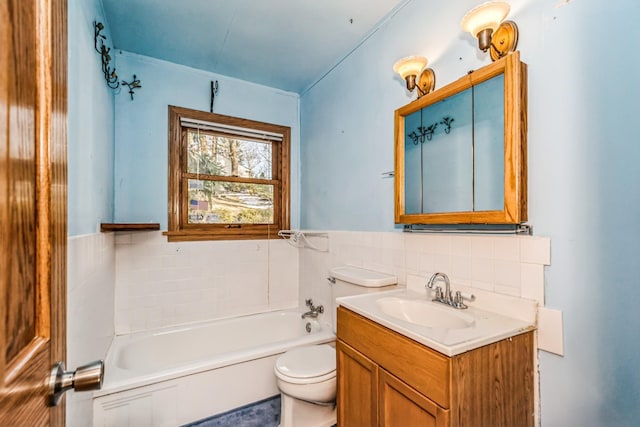 bathroom featuring a washtub, vanity, toilet, and tile walls