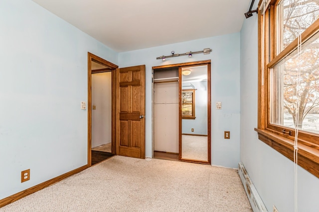 unfurnished bedroom featuring carpet flooring, baseboard heating, and a closet