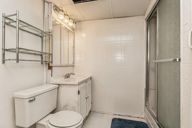 bathroom with vanity, toilet, walk in shower, and tile walls