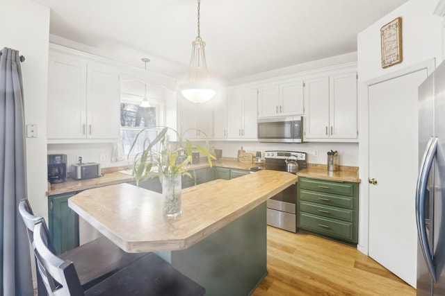 kitchen with decorative light fixtures, white cabinetry, butcher block counters, and stainless steel appliances