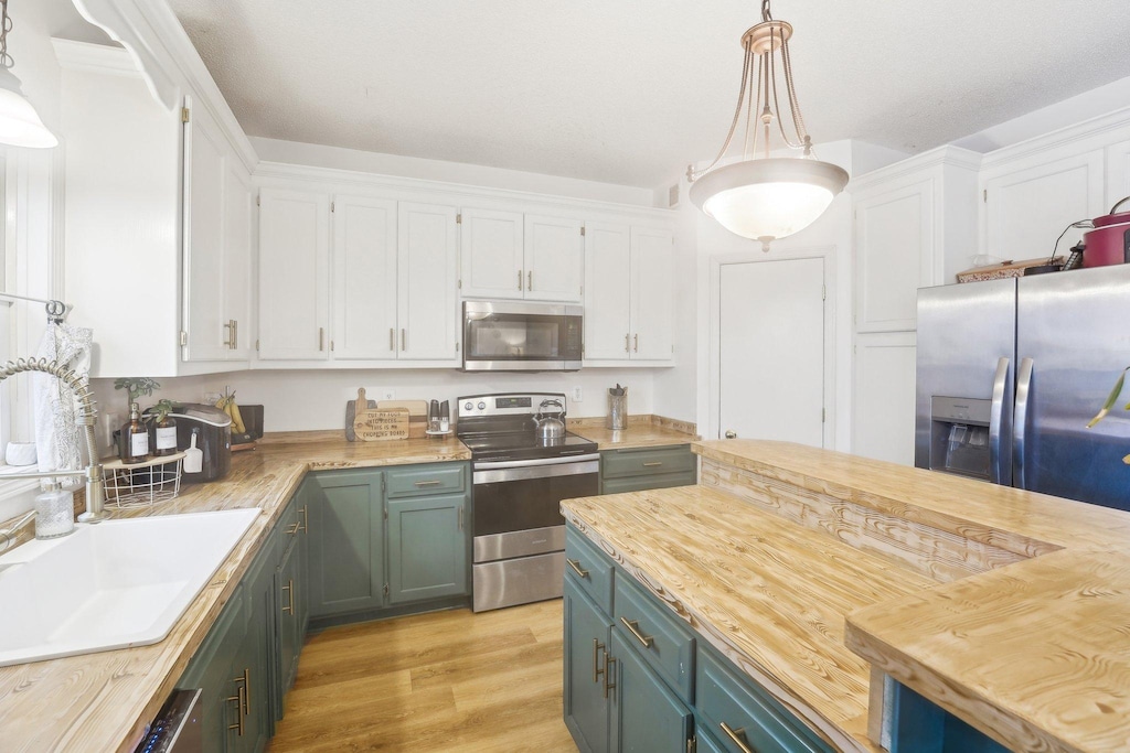 kitchen featuring decorative light fixtures, appliances with stainless steel finishes, and white cabinetry