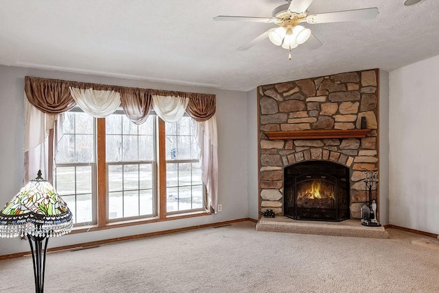 unfurnished living room with carpet flooring, ceiling fan, and a stone fireplace