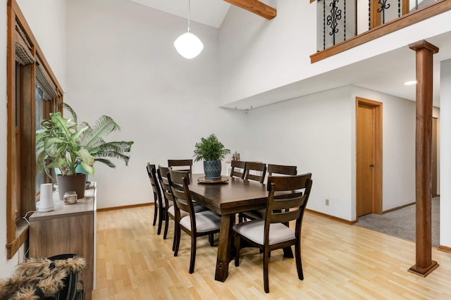 dining area featuring a towering ceiling, light hardwood / wood-style flooring, and decorative columns