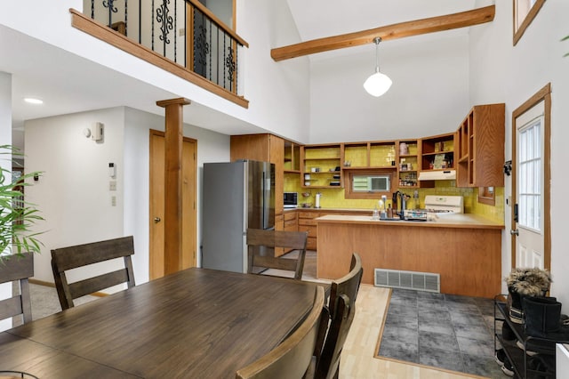 dining area with beamed ceiling, light hardwood / wood-style floors, and a high ceiling