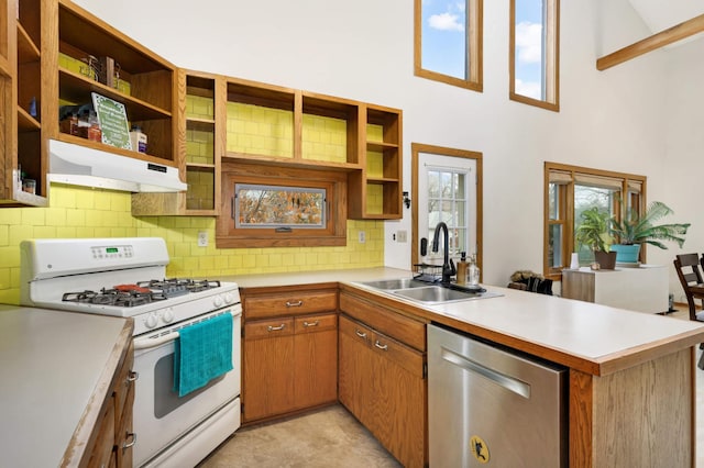 kitchen featuring white gas range, dishwasher, sink, kitchen peninsula, and decorative backsplash