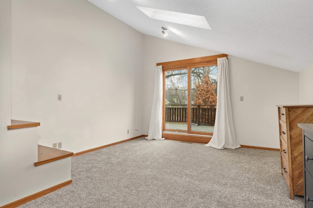 interior space with a textured ceiling, carpet floors, and lofted ceiling with skylight