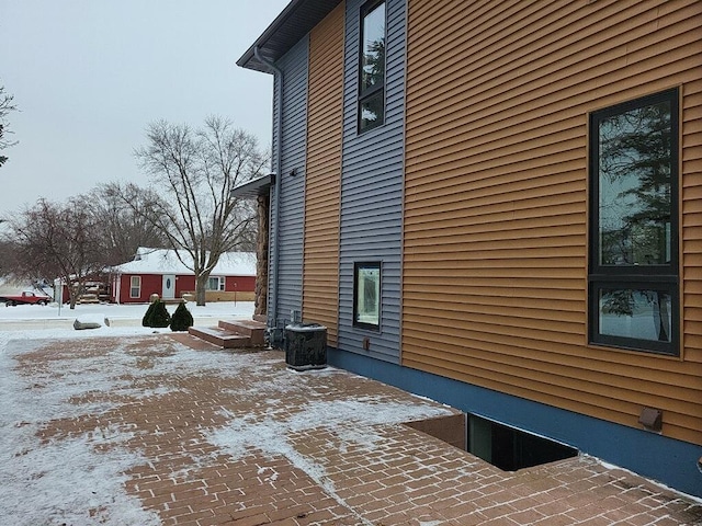 view of snowy exterior with cooling unit