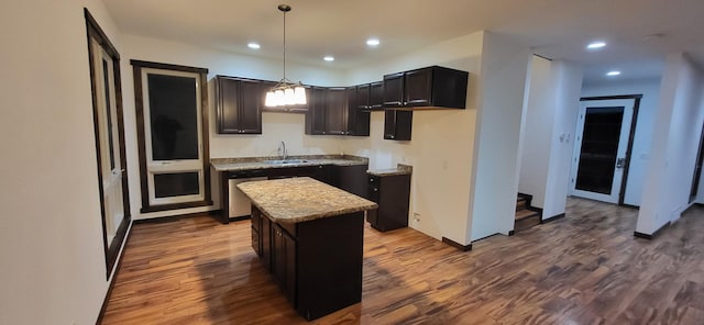 kitchen featuring a kitchen island, pendant lighting, dishwasher, sink, and hardwood / wood-style flooring