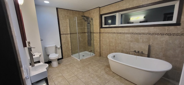 bathroom with tile patterned flooring, tile walls, toilet, and separate shower and tub