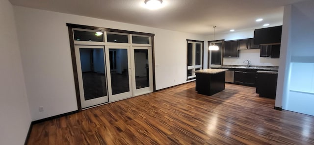 kitchen with dark hardwood / wood-style flooring, a center island, sink, and hanging light fixtures