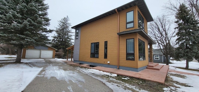 view of snowy exterior featuring a garage and an outdoor structure