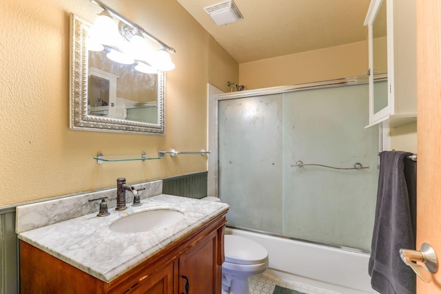 full bathroom with vanity, bath / shower combo with glass door, and toilet