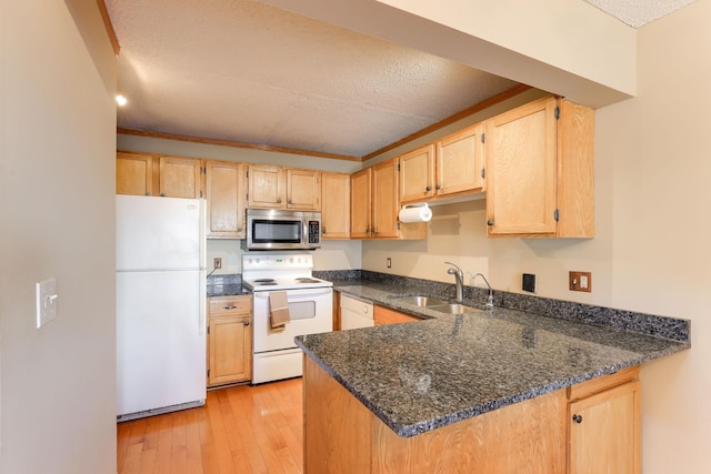 kitchen featuring sink, light wood-type flooring, kitchen peninsula, white appliances, and dark stone counters