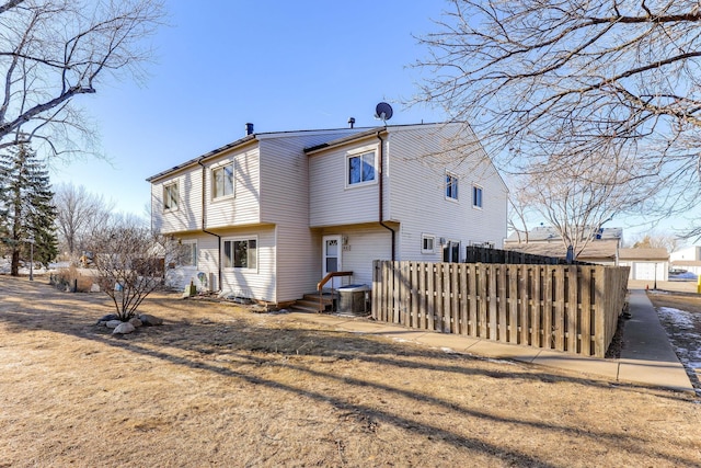 rear view of property with a yard and central air condition unit