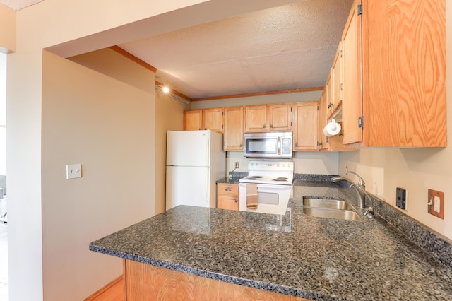 kitchen with sink, white appliances, crown molding, dark stone countertops, and kitchen peninsula