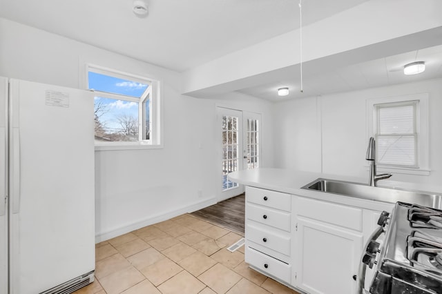 kitchen featuring range with gas cooktop, white fridge, sink, white cabinetry, and french doors