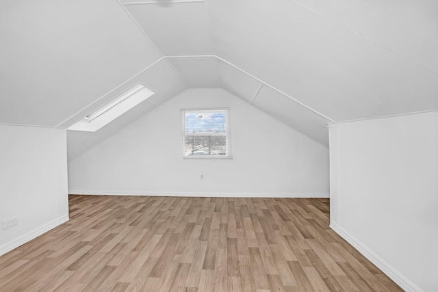 additional living space with lofted ceiling with skylight and light hardwood / wood-style flooring