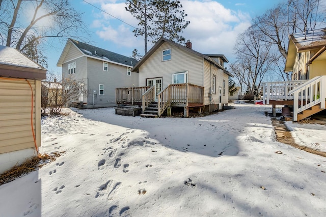 snow covered back of property with a wooden deck and french doors