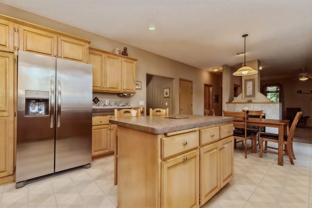 kitchen with pendant lighting, ceiling fan, a kitchen island, stainless steel fridge with ice dispenser, and light brown cabinets