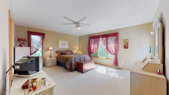 carpeted bedroom featuring ceiling fan and a textured ceiling