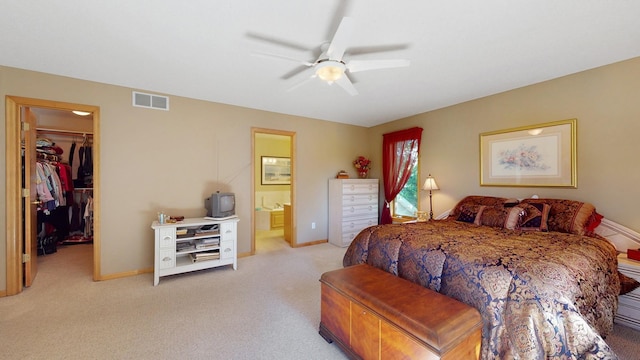 carpeted bedroom featuring a walk in closet, connected bathroom, ceiling fan, and a closet