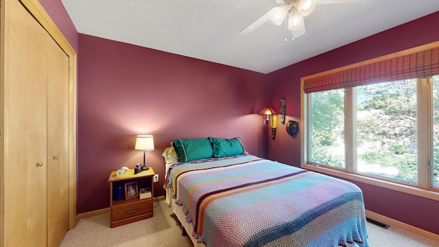 bedroom featuring light carpet, ceiling fan, and a closet