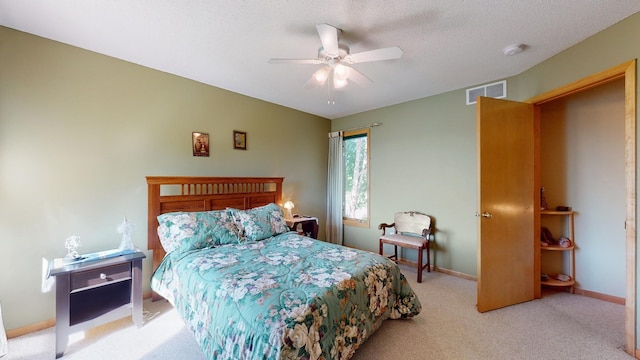 carpeted bedroom featuring ceiling fan and a textured ceiling