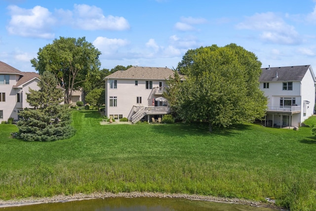 rear view of property with a deck with water view and a yard