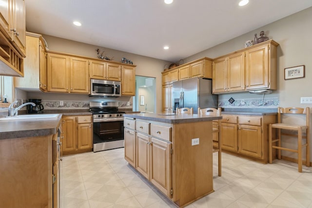 kitchen with dark countertops, a center island, recessed lighting, stainless steel appliances, and a sink