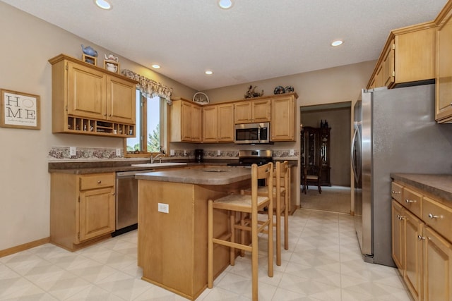 kitchen with dark countertops, a center island, a breakfast bar area, recessed lighting, and stainless steel appliances