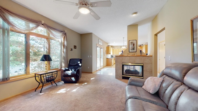 carpeted living room with a tiled fireplace, a textured ceiling, a ceiling fan, and baseboards