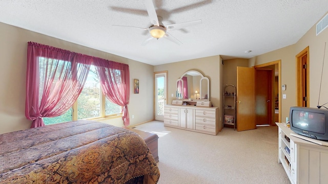 bedroom with ceiling fan, light colored carpet, visible vents, and a textured ceiling