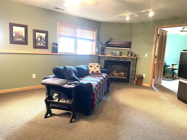 living area featuring carpet, baseboards, visible vents, a tile fireplace, and a textured ceiling