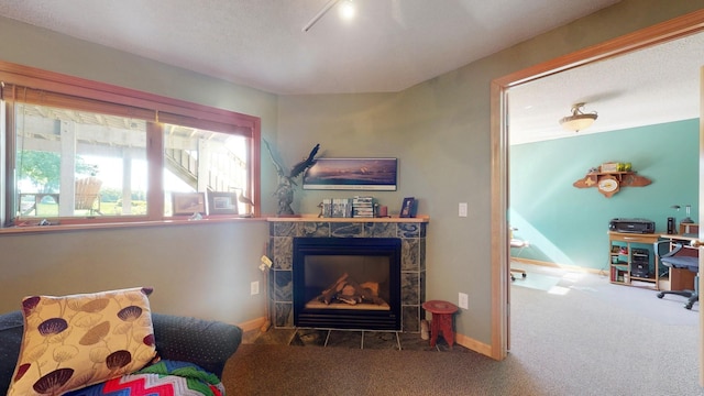 living area with baseboards, carpet, and a tiled fireplace