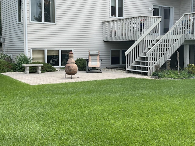 rear view of house with stairway, a yard, a patio area, and a wooden deck