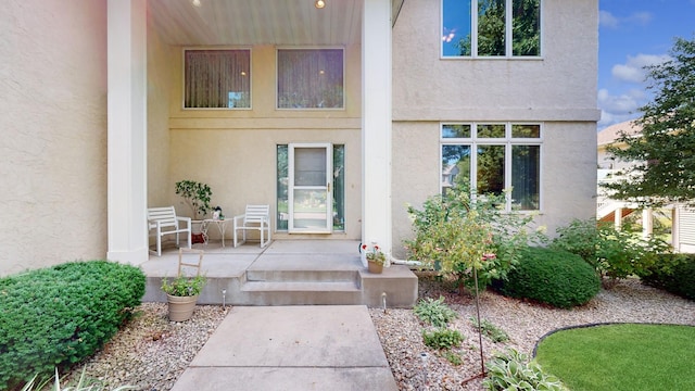 property entrance featuring covered porch and stucco siding