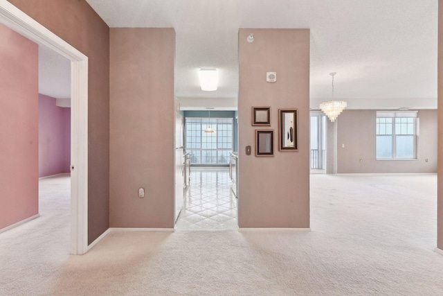 hallway with light carpet and a chandelier