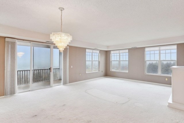 empty room with a healthy amount of sunlight, carpet floors, and an inviting chandelier