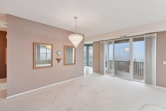 empty room with carpet, a textured ceiling, and an inviting chandelier