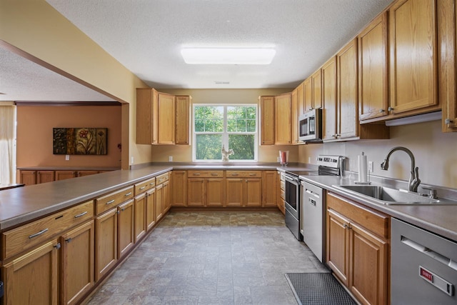 kitchen with kitchen peninsula, a textured ceiling, stainless steel appliances, and sink