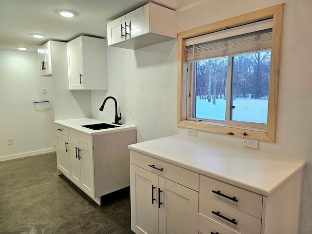 kitchen featuring dark carpet, white cabinets, and sink