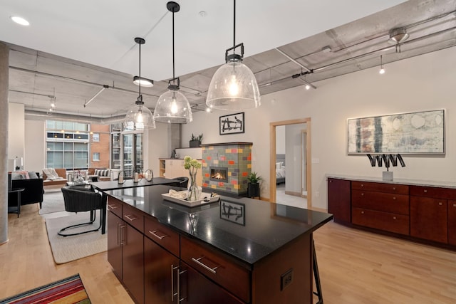 kitchen with rail lighting, decorative light fixtures, light hardwood / wood-style flooring, a fireplace, and a kitchen island