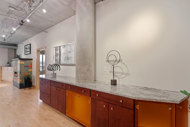 kitchen with a multi sided fireplace, light stone countertops, and light wood-type flooring