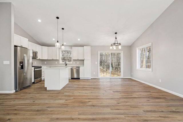 kitchen with pendant lighting, stainless steel appliances, a kitchen island, and white cabinetry