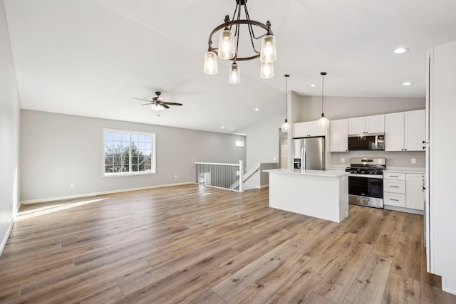 kitchen featuring appliances with stainless steel finishes, decorative light fixtures, white cabinets, light hardwood / wood-style floors, and a kitchen island