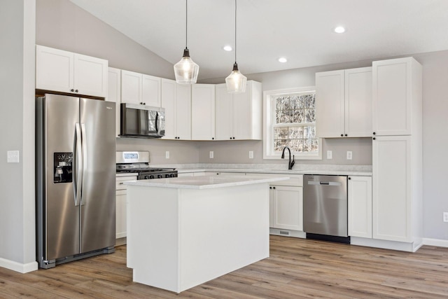 kitchen with appliances with stainless steel finishes, white cabinets, a center island, hanging light fixtures, and lofted ceiling