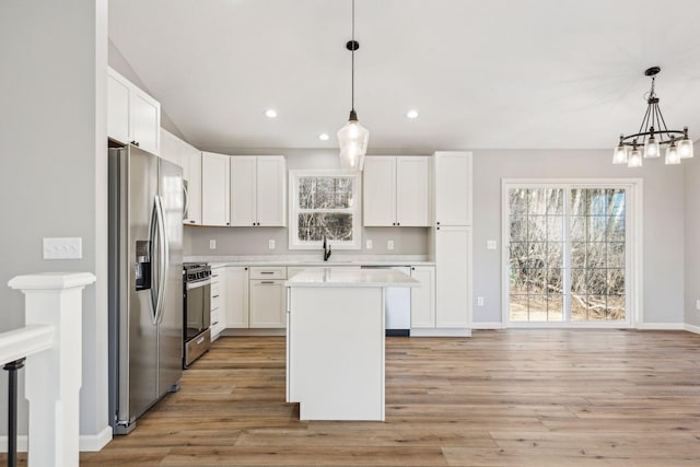 kitchen with appliances with stainless steel finishes, a center island, white cabinetry, and pendant lighting